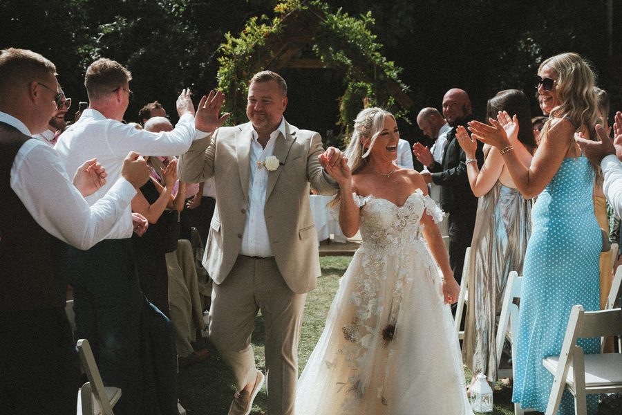 A newly married couple walking back down the aisle through a guard of applauding guests.