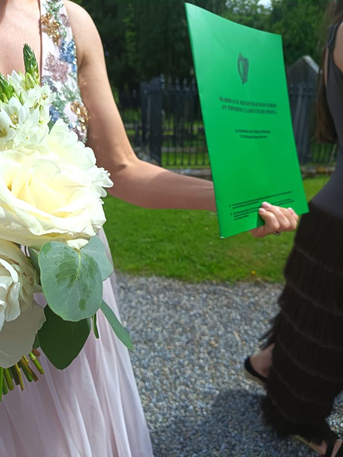 A bride's white rose bouquet beside the green Irish marriage registration form.